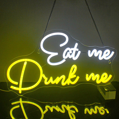 Op de afbeelding staat een opvallend LED-neonbord met de tekst "Eat Me Drink Me" in een speels, cursief lettertype.