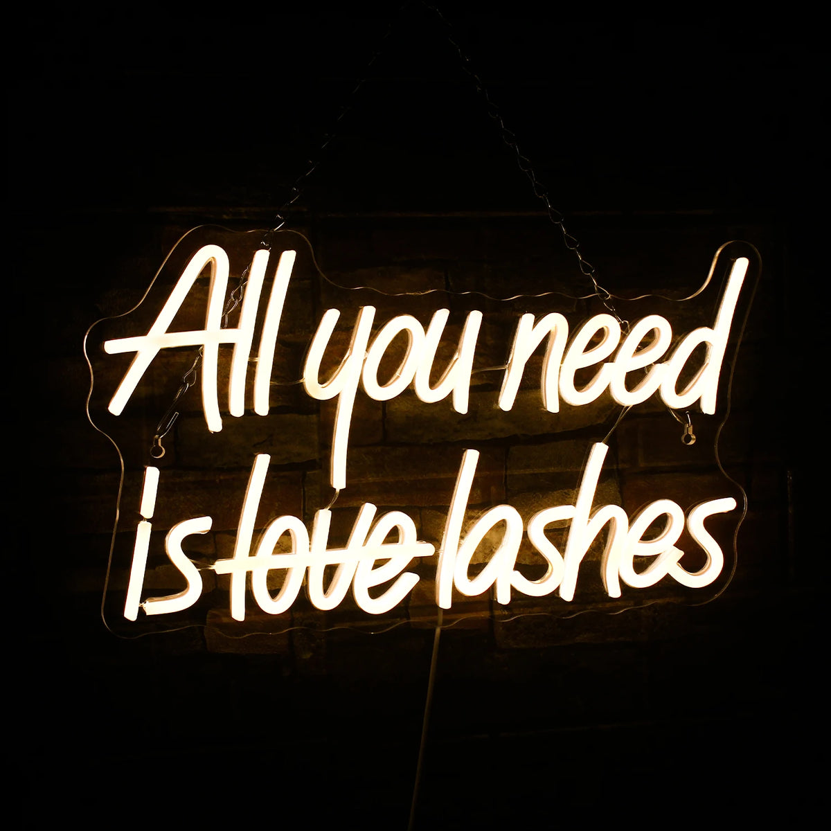 Op de afbeelding staat een opvallend led-neonbord met de tekst "All You Need is Lashes" in elegante, cursieve letters.