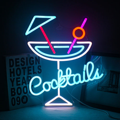 De afbeelding toont een levendig LED-neonbord met het woord "Cocktails" in een speels, cursief lettertype.
