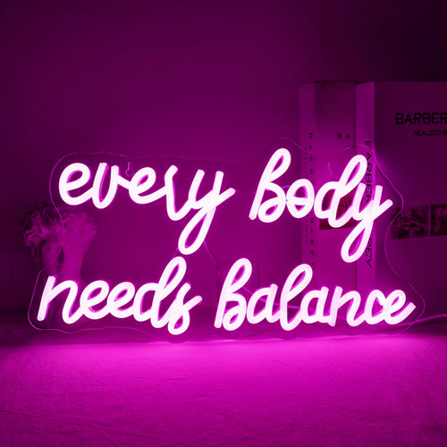 Op de afbeelding is een levendig LED-neonbord te zien met de tekst "Every Body Needs Balance".