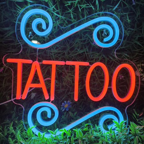 Een verlicht LED-neonbord toont het woord "TATTOO" in vette hoofdletters.