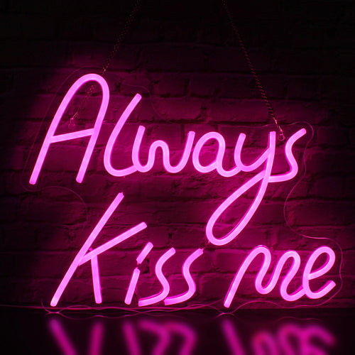 Op de afbeelding staat een stijlvol, handgemaakt LED-neonbord met de tekst "Always Kiss Me" in schuinschrift.