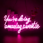 Een opvallend LED-neonbord met de tekst "You're Doing Amazing Sweetie" in elegant, cursief handschrift.