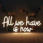 Op de afbeelding is een handgemaakt LED-neonbord te zien met de tekst "All We Have Is Now" in levendige, lichtgevende letters.