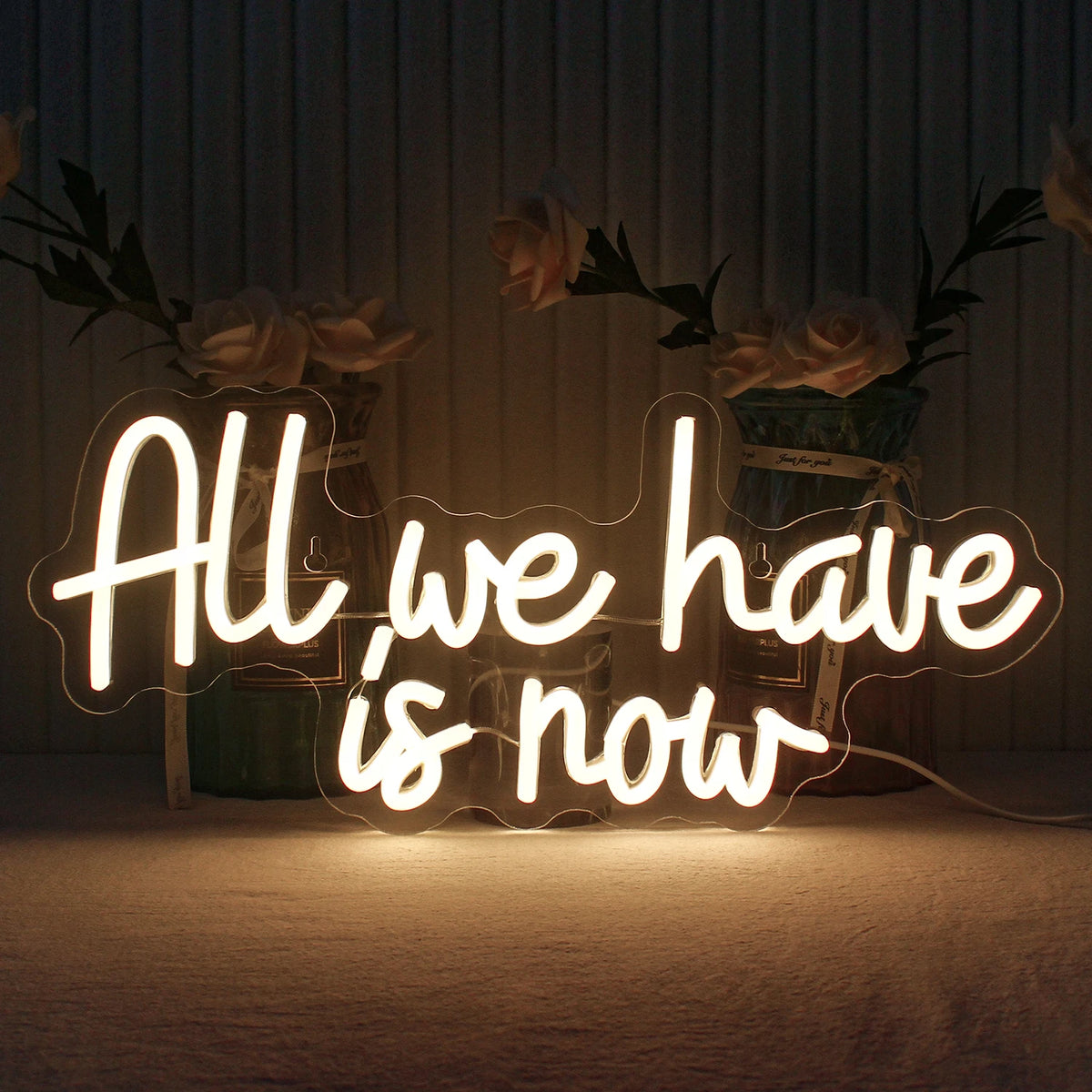 Op de afbeelding is een handgemaakt LED-neonbord te zien met de tekst "All We Have Is Now" in levendige, lichtgevende letters.