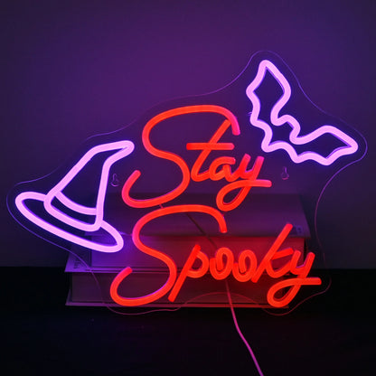 The image features a handcrafted LED neon sign displaying the words "Stay Spooky" in a playful, flowing script.