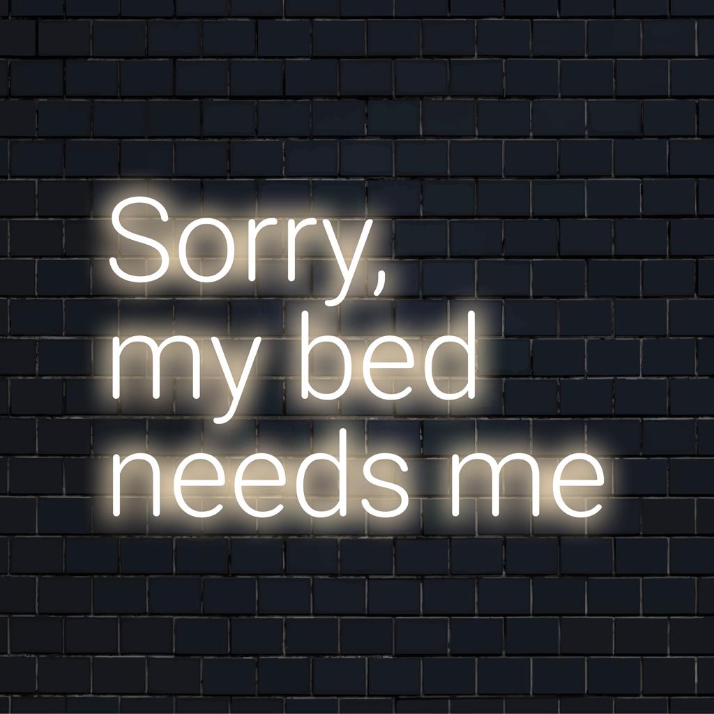 Een op maat gemaakt LED-neonbord met de tekst Sorry, My Bed Needs Me in felle, speelse letters voor een unieke slaapkamerinrichting.