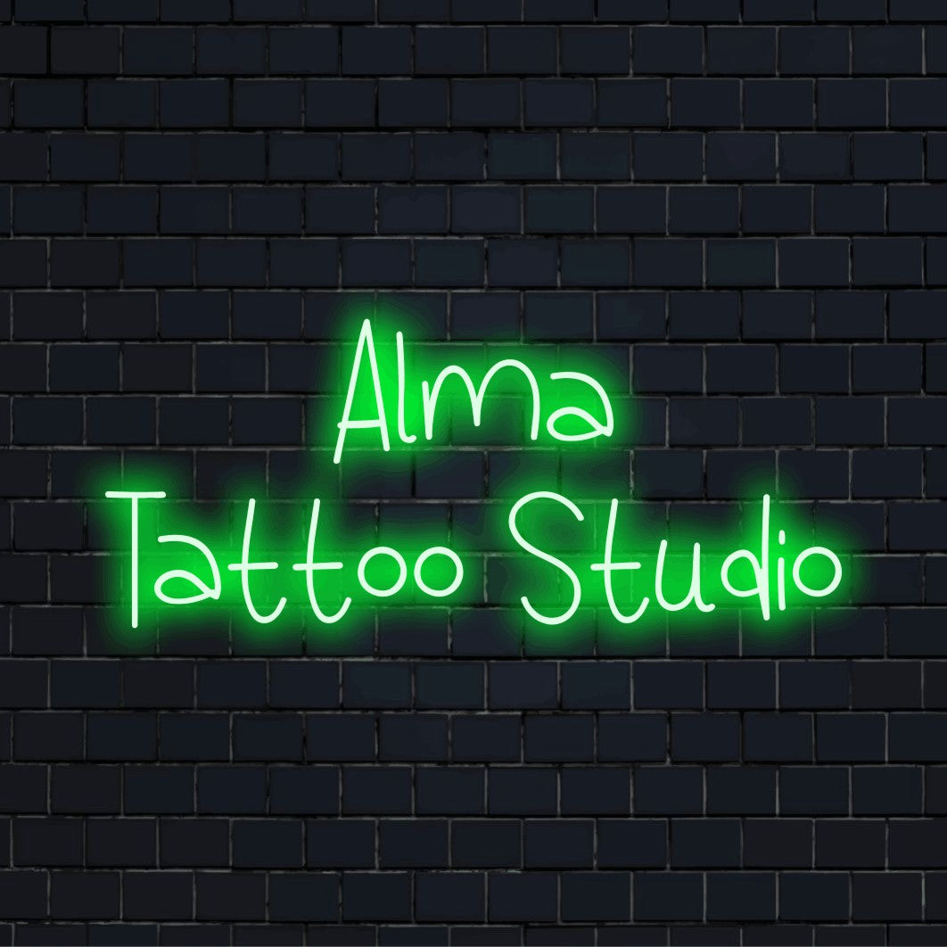 Alma Tattoo Studio Personalized LED Neon Sign, bright neon glow against black brick wall