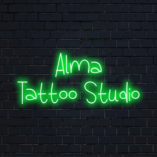 Alma Tattoo Studio Personalized LED Neon Sign, bright neon glow against black brick wall