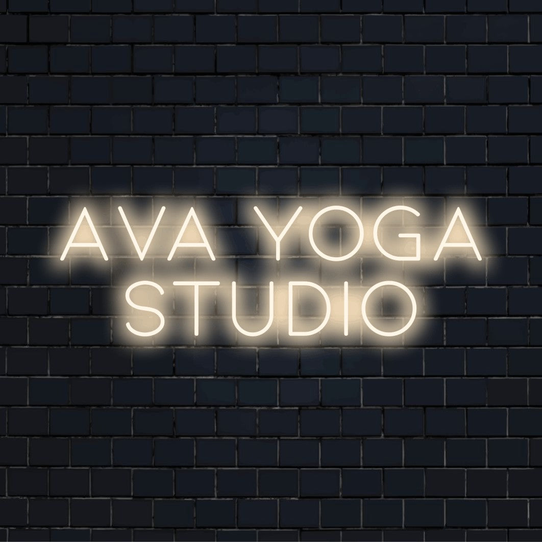 Ava Yoga Studio Personalized Neon Light with glowing neon text on dark brick wall