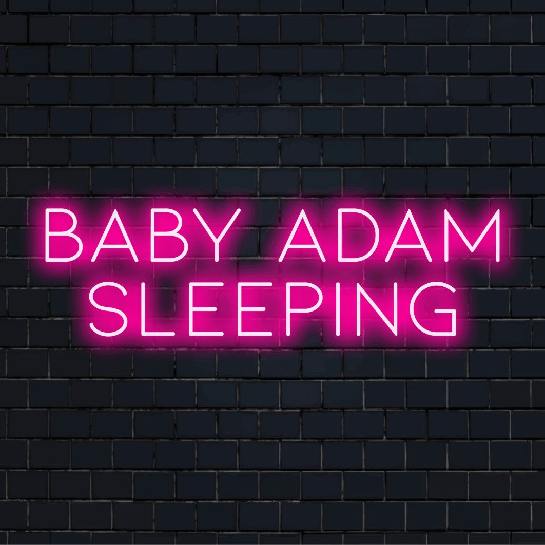 Baby Adam Sleeping Custom Name Neon Sign, glowing wall decor against brick backdrop