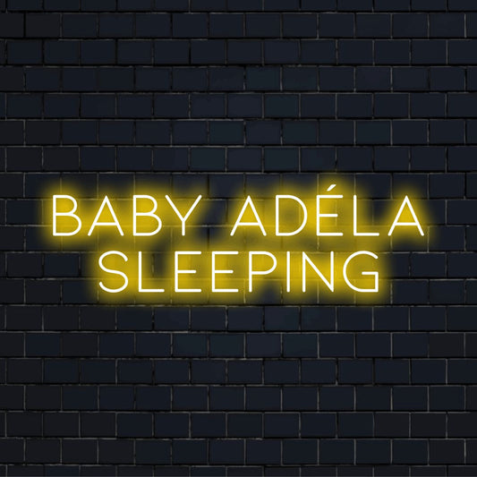 Baby Adela Sleeping Personalized Neon Light with glowing lettering on black brick background