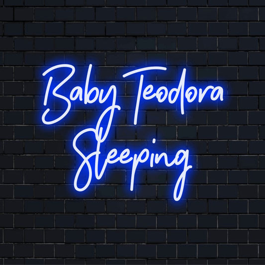 Baby Teodora Sleeping Personalized Neon Light with bright neon lettering against black brick wall