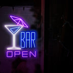 The photo shows a neon sign with a cocktail with an umbrella on the left and the text 'open bar' on the right. This neon sign is ideal for bars, both indoor and outdoor.