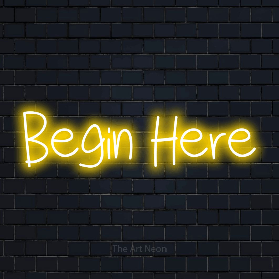 "Begin Here" LED neon sign on a black brick wall