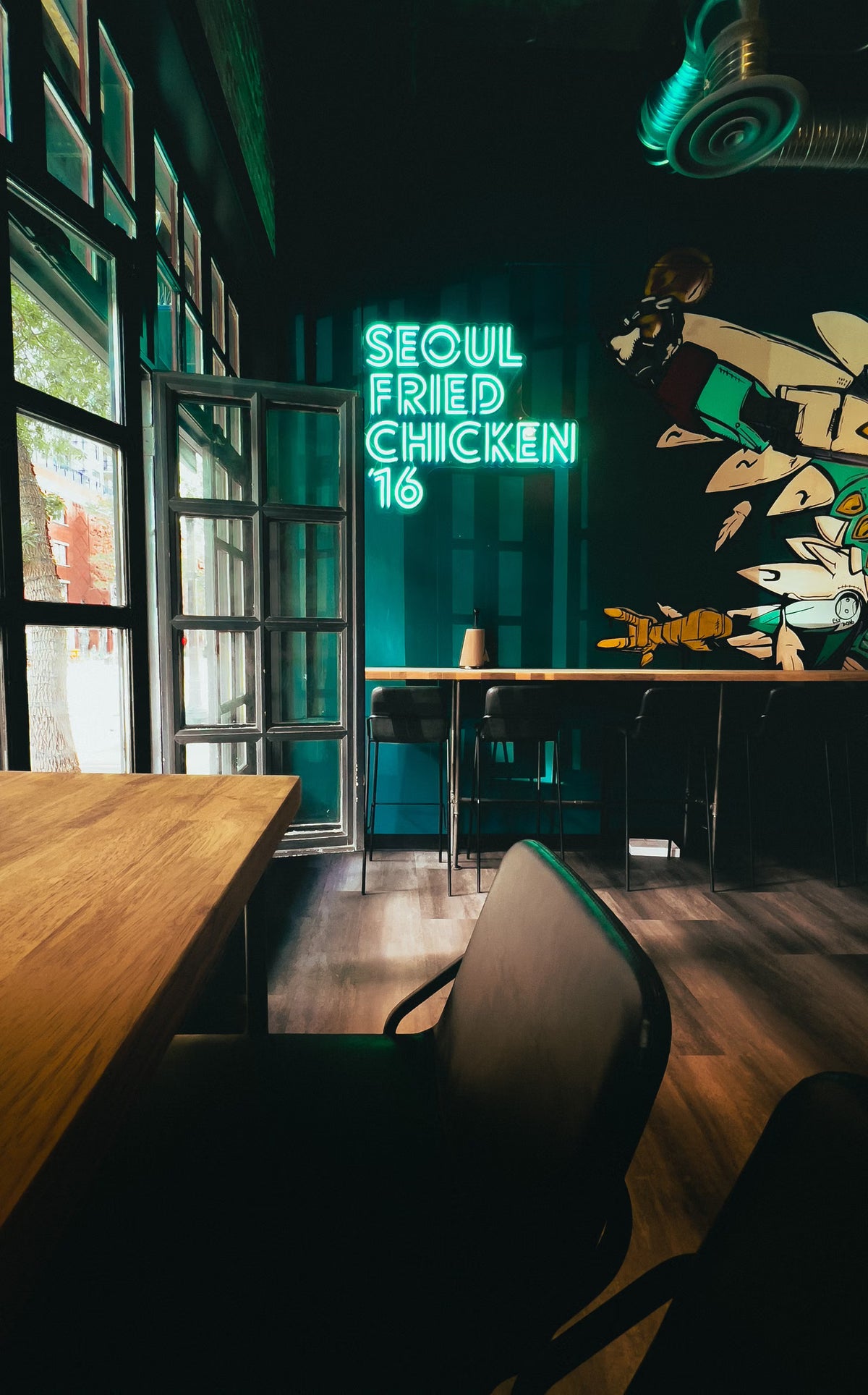 Green LED neon restaurant sign beside dining tables and large windows
