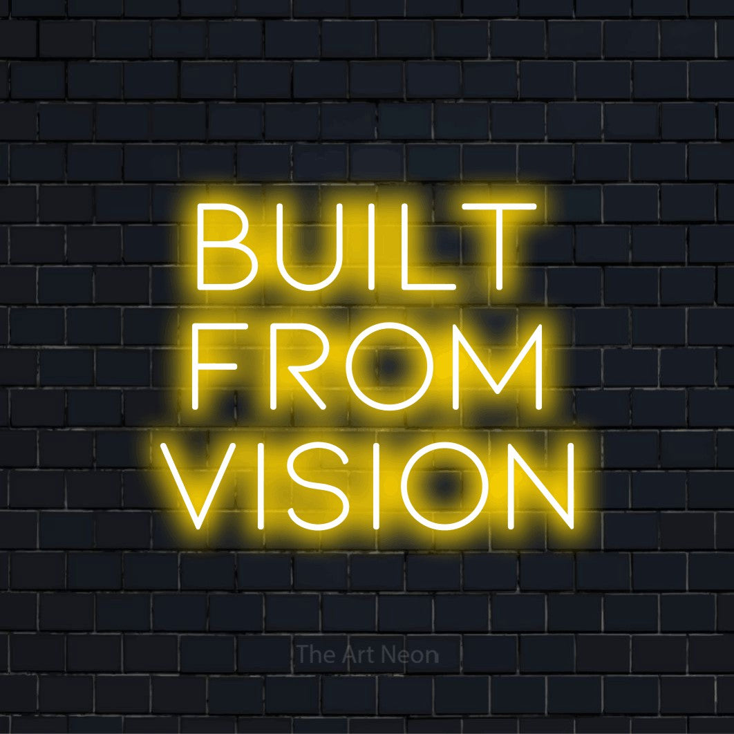 "Built From Vision" script-style LED neon sign on a black brick wall