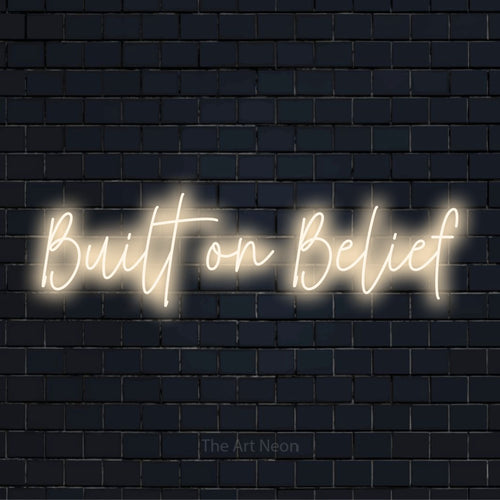 "Built On Belief" LED neon sign on a black brick wall