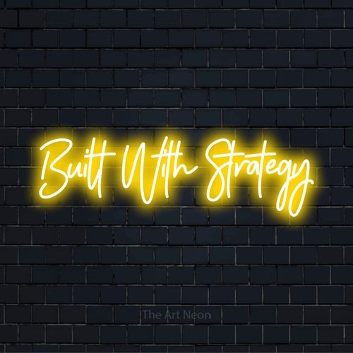 "Built With Strategy" script-style LED neon sign on a black brick wall