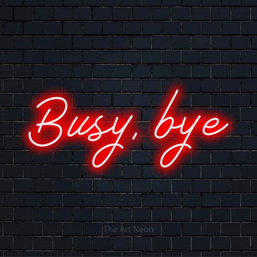 "Busy, Bye" script-style LED neon sign on a black brick wall