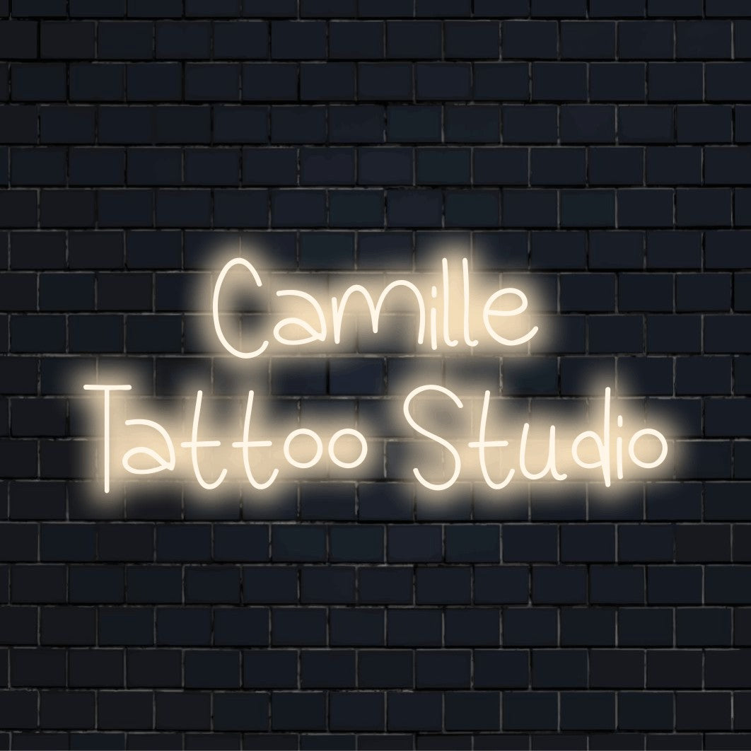 Camille Tattoo Studio Personalized LED Neon Sign, glowing wall decor against brick backdrop