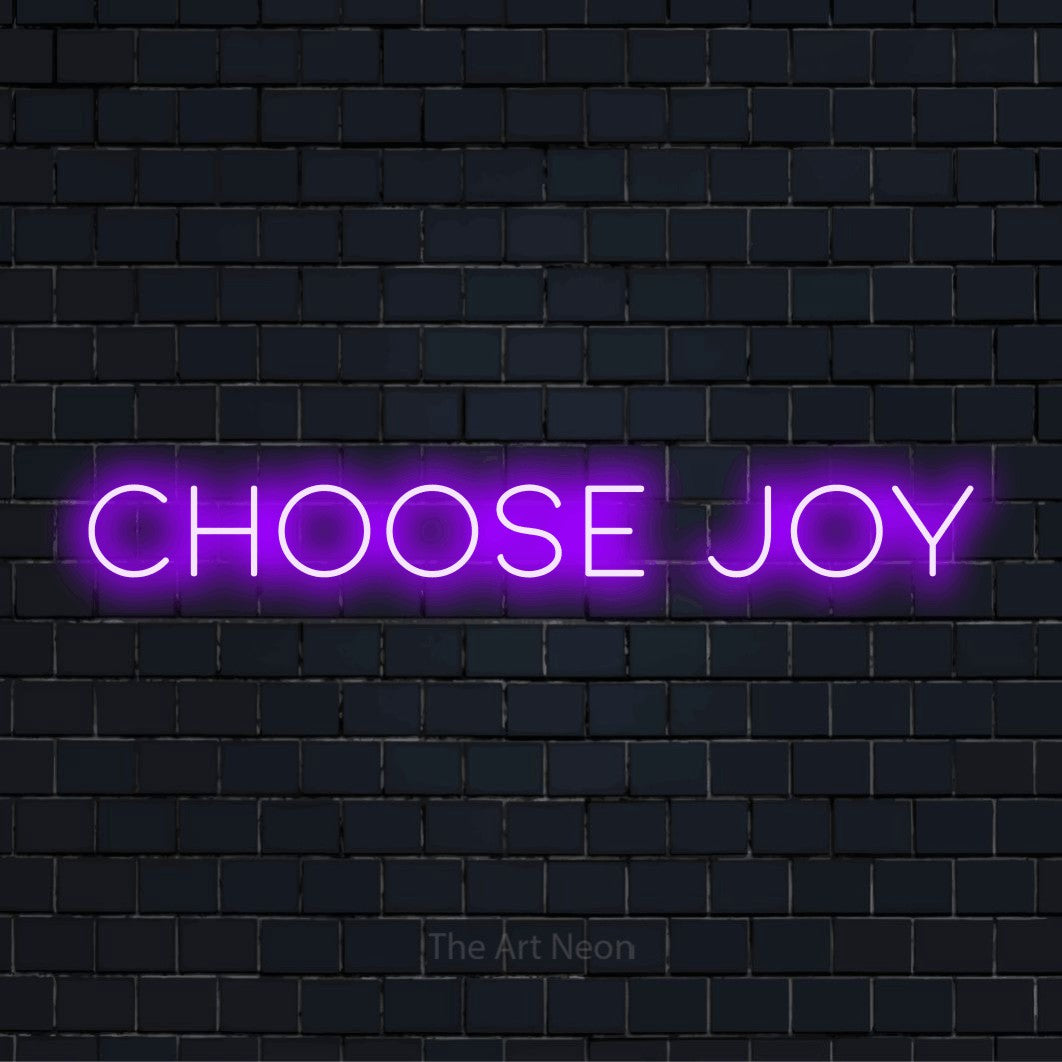 "Choose Joy" glowing LED neon sign on a black brick wall