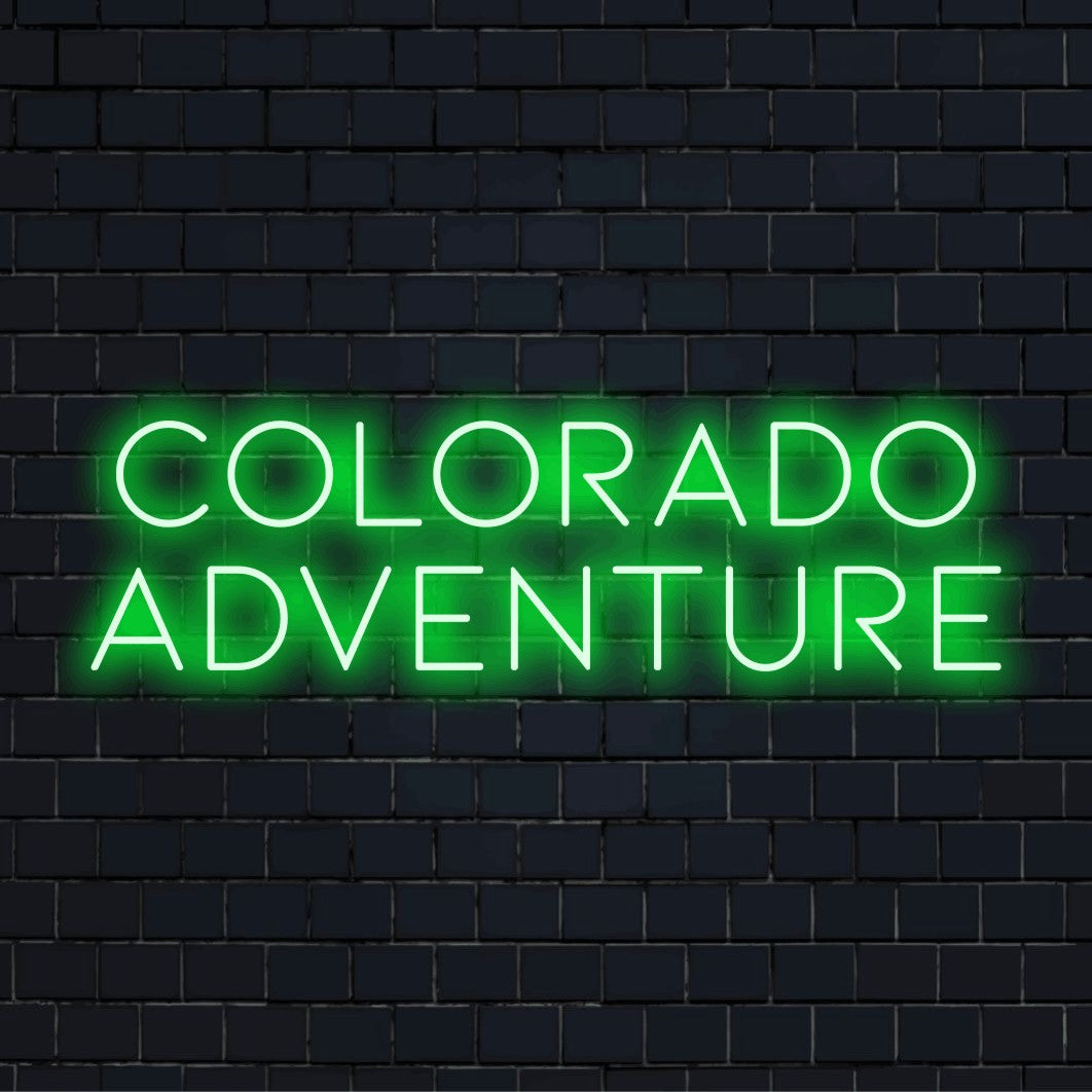 Colorado Adventure Neon Sign, bright neon lettering against black brick wall