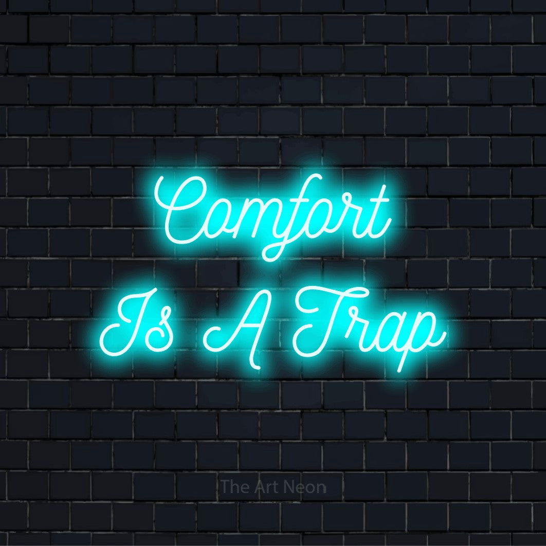 "Comfort Is A Trap" script-style LED neon sign on a black brick wall