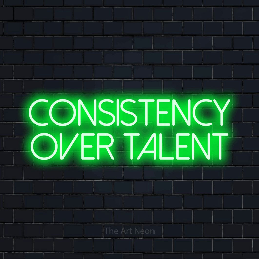 "Consistency Over Talent" LED neon sign on a black brick wall