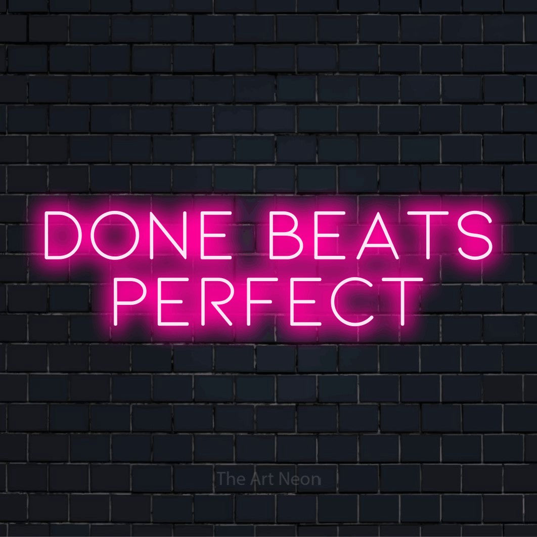 "Done Beats Perfect" script-style LED neon sign on a black brick wall