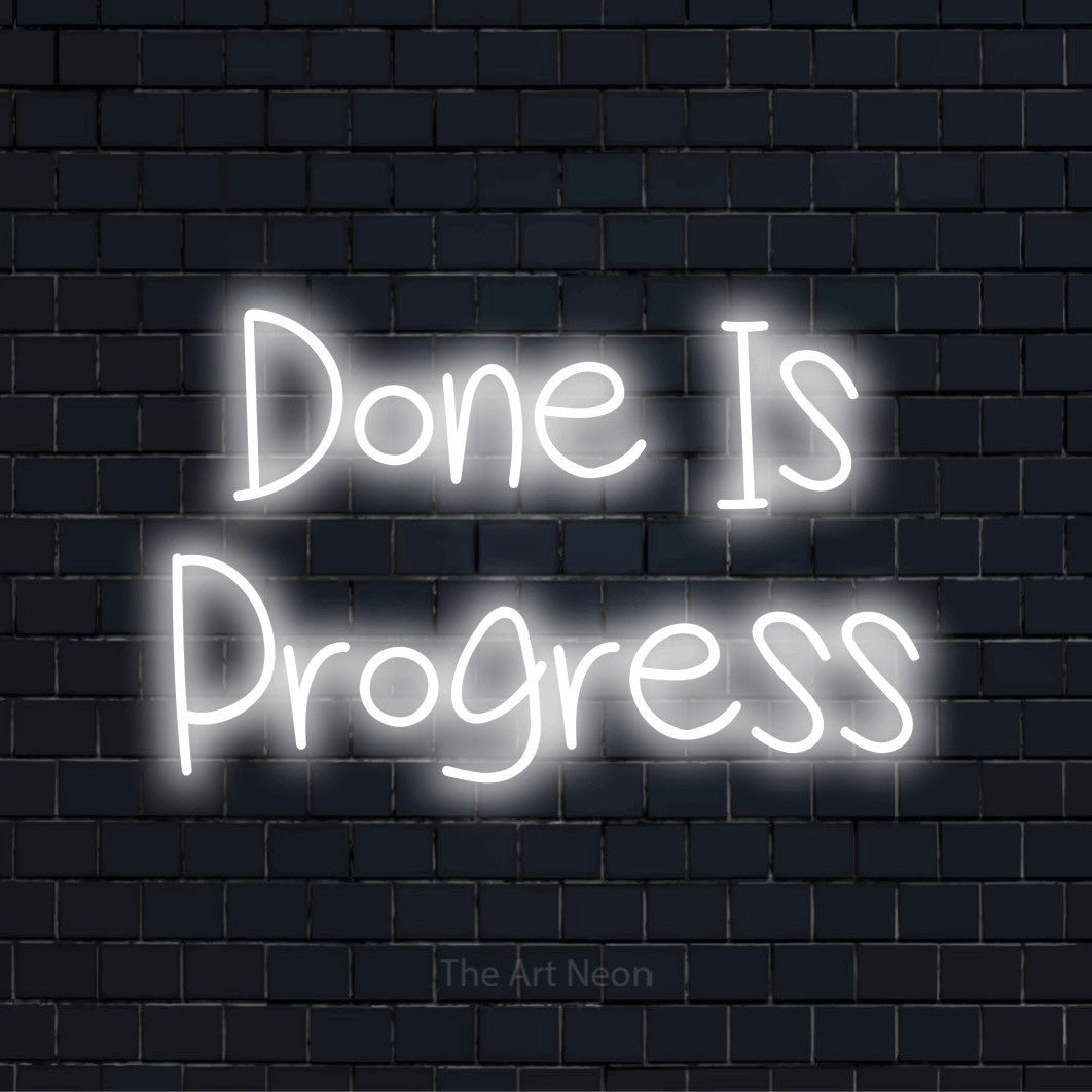 "Done Is Progress" text design with neon effect on a black brick wall