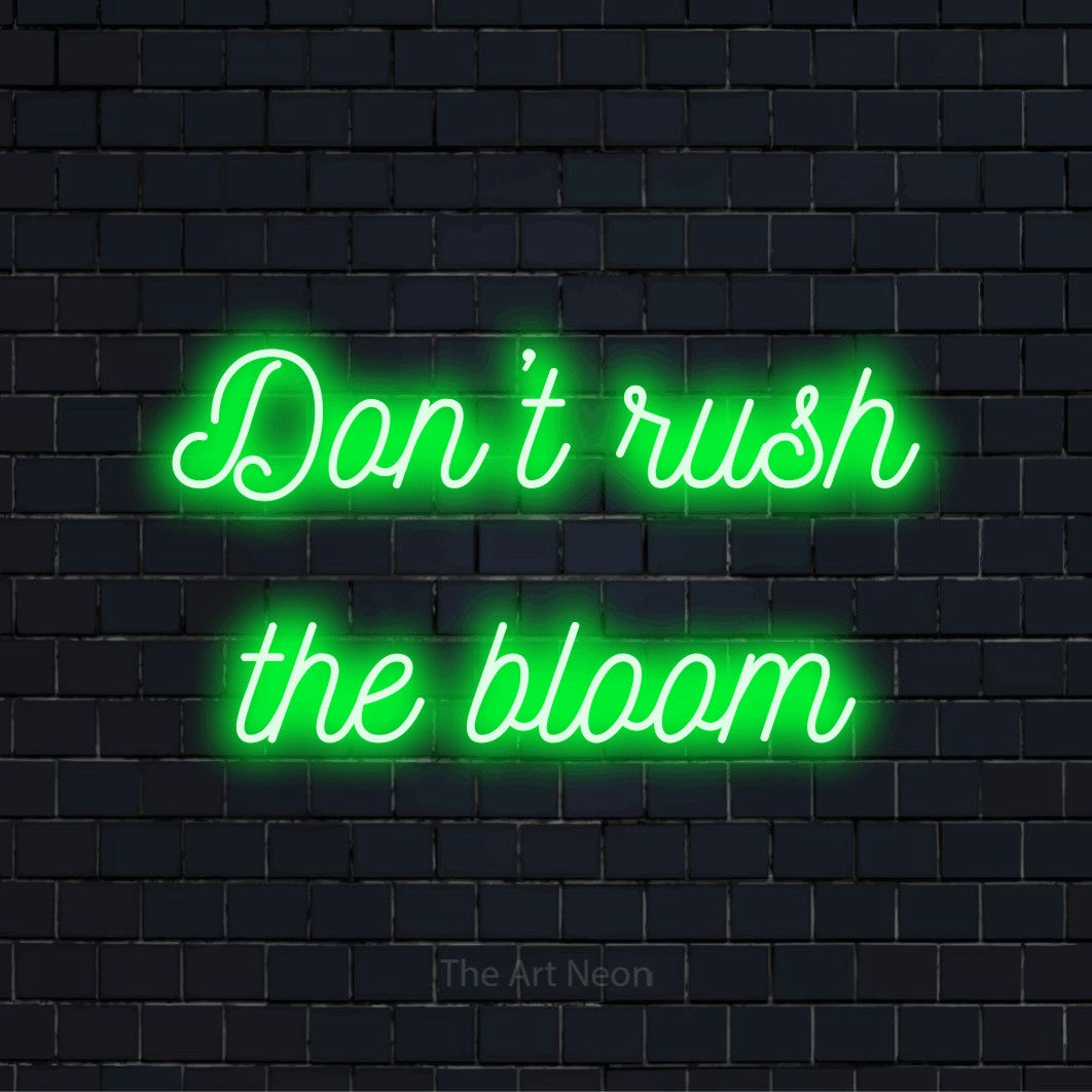 "Don’t Rush The Bloom" LED neon sign on a black brick wall