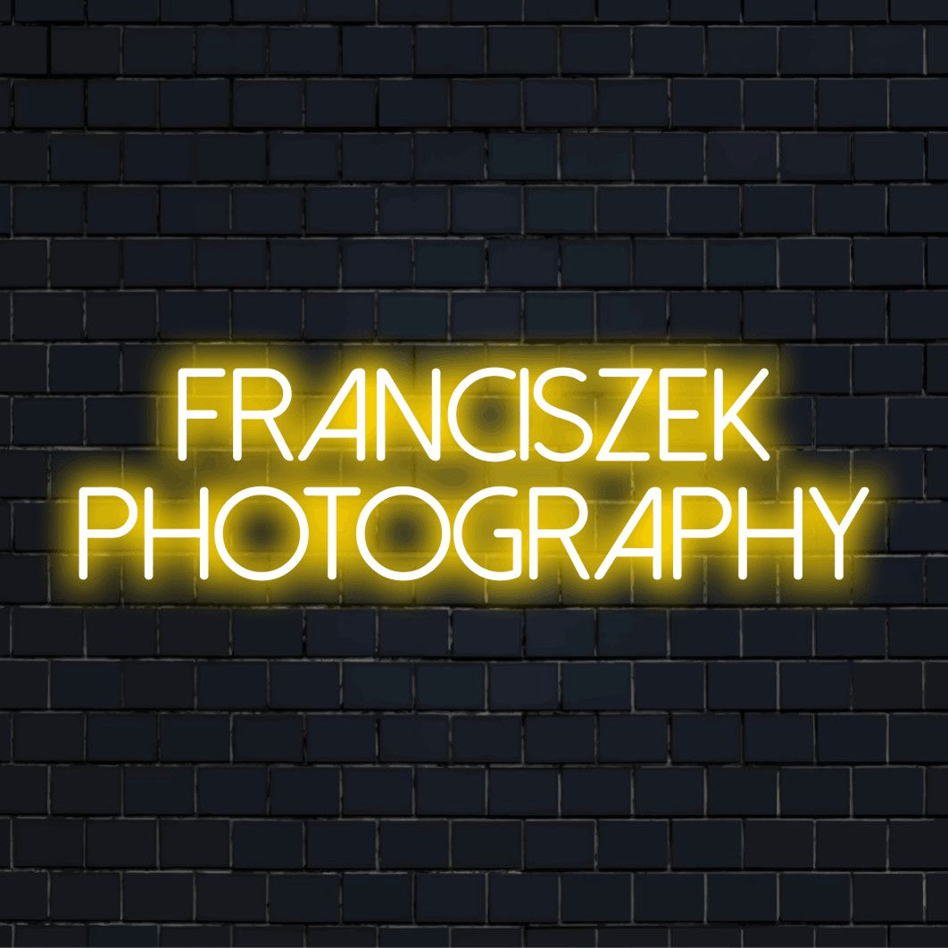 Franciszek Photography Custom Name Neon Sign, glowing lettering on dark brick background