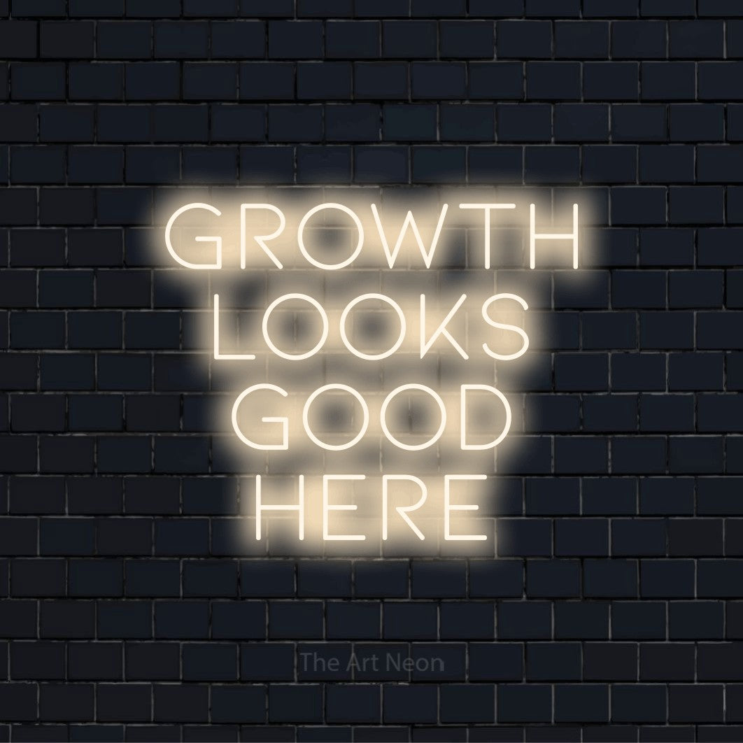 "Growth Looks Good Here" glowing LED neon sign on a black brick wall