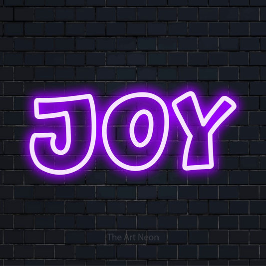 "Joy" glowing LED neon sign on a black brick wall