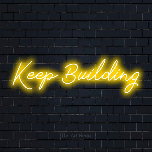"Keep Building" neon text design on a black brick wall