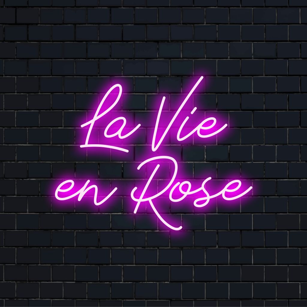 La Vie En Rose LED Neon Sign, glowing lettering on black brick background