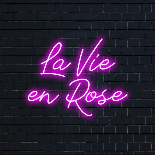 La Vie En Rose LED Neon Sign, glowing lettering on black brick background