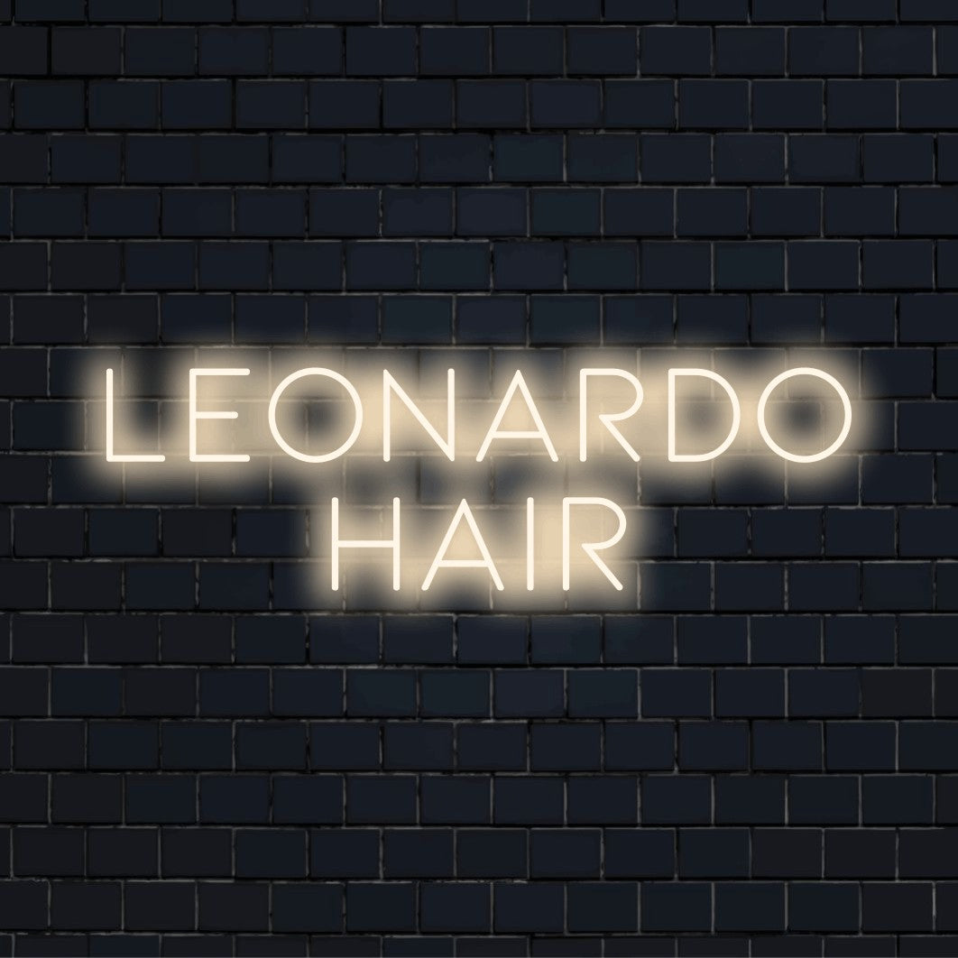 Leonardo Hair Personalized Neon Light with glowing neon text against black brick wall