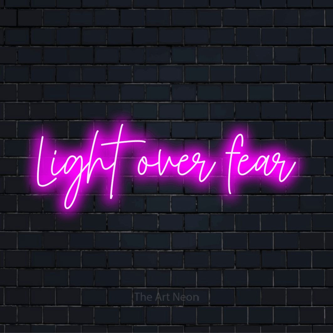 "Light Over Fear" neon text design on a black brick wall