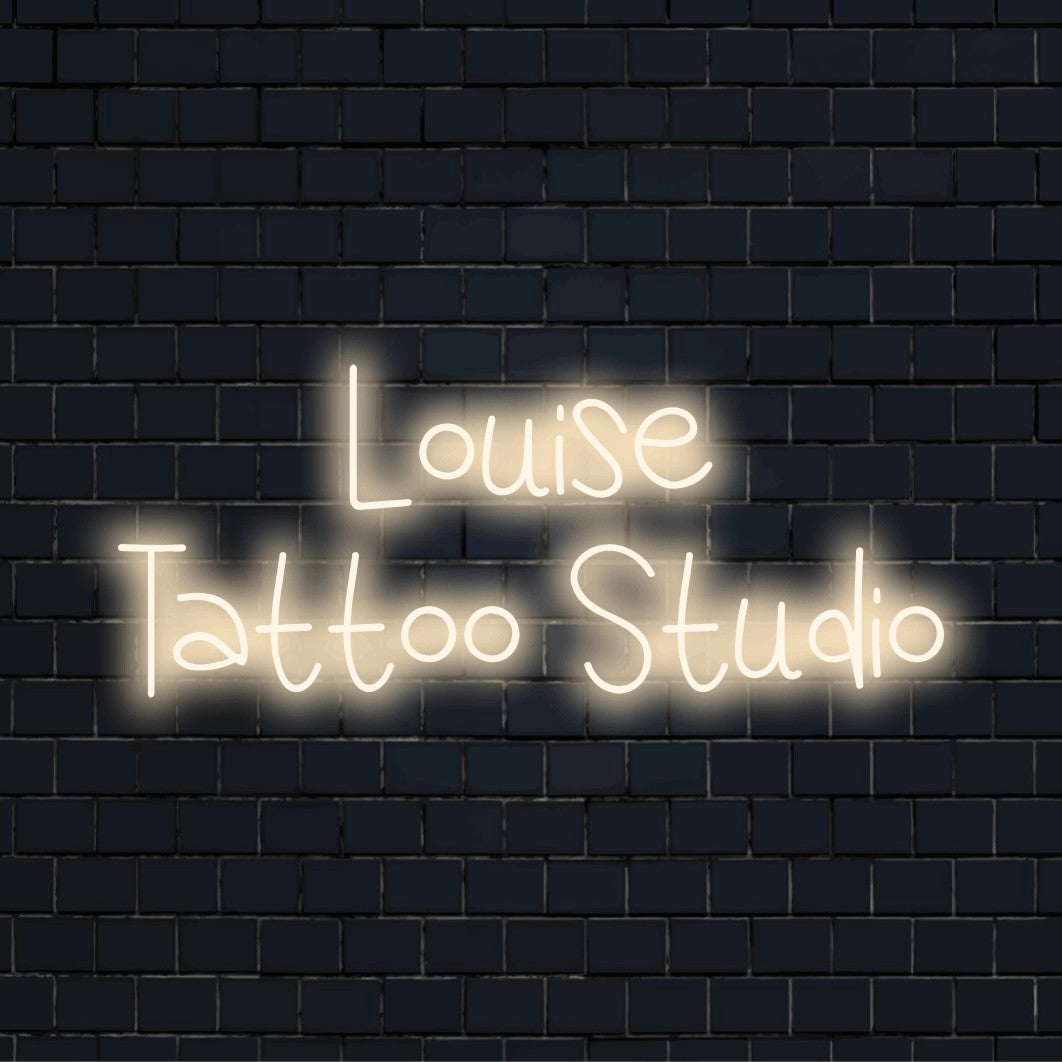 Louise Tattoo Studio Custom Name Neon Sign, glowing wall decor against brick backdrop