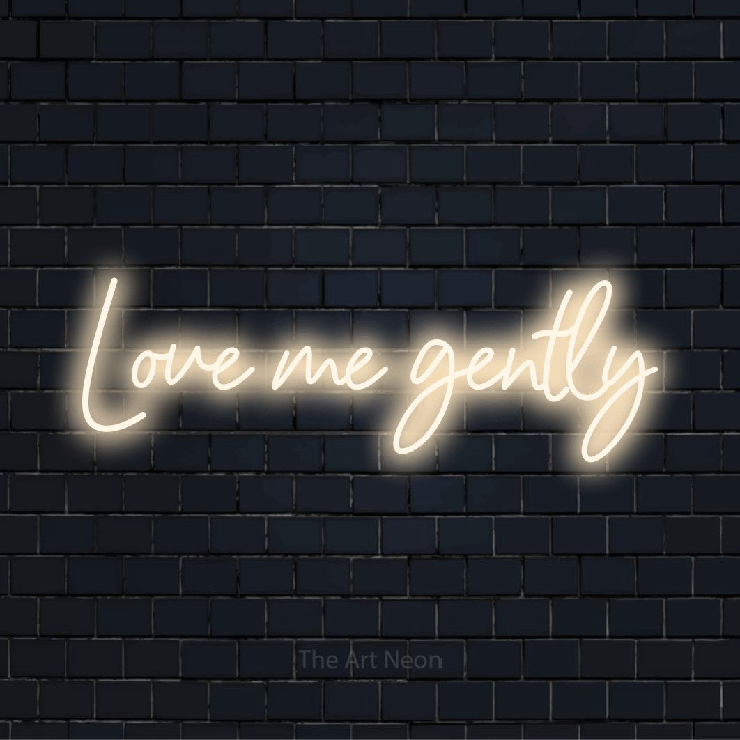 "Love Me Gently" text design with neon effect on a black brick wall