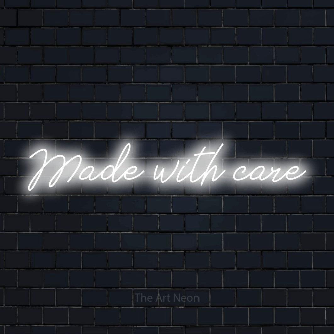 "Made With Care" script-style LED neon sign on a black brick wall