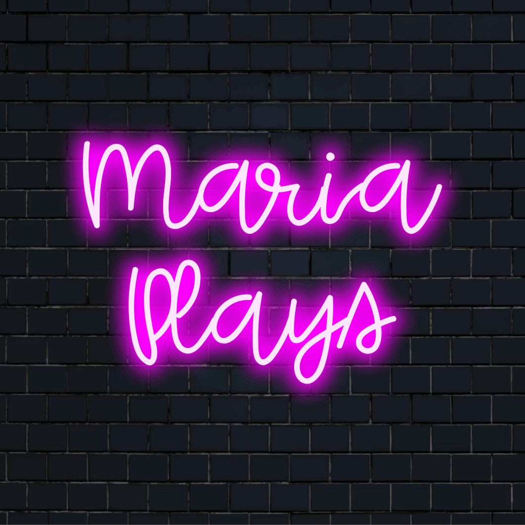 Maria Plays Custom Name Neon Sign, bright neon lettering against black brick wall