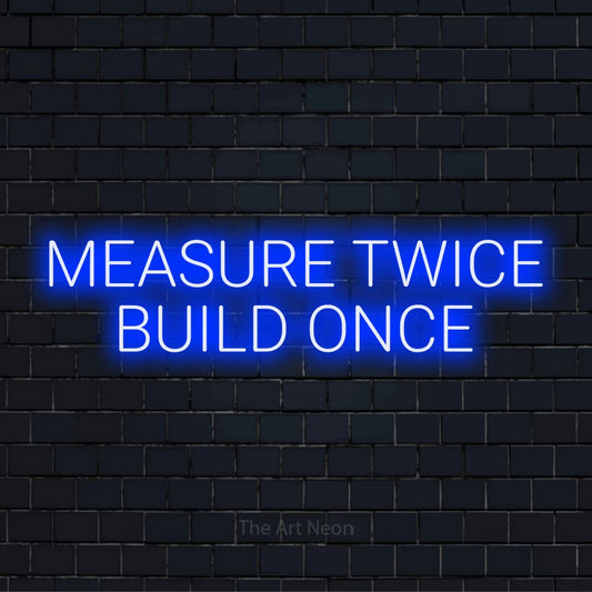 "Measure Twice Build Once" glowing LED neon sign on a black brick wall