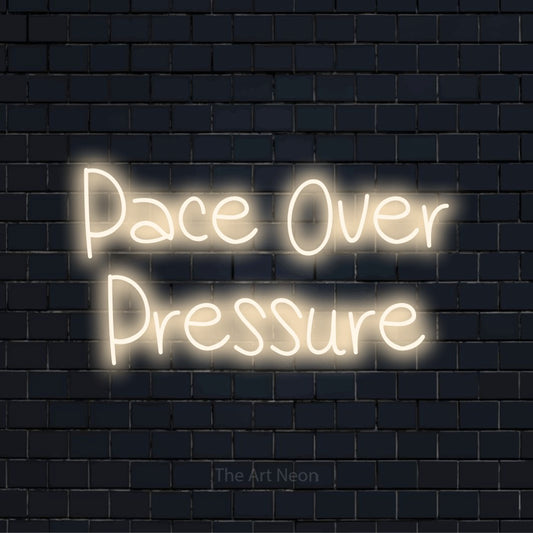 "Pace Over Pressure" script-style LED neon sign on a black brick wall