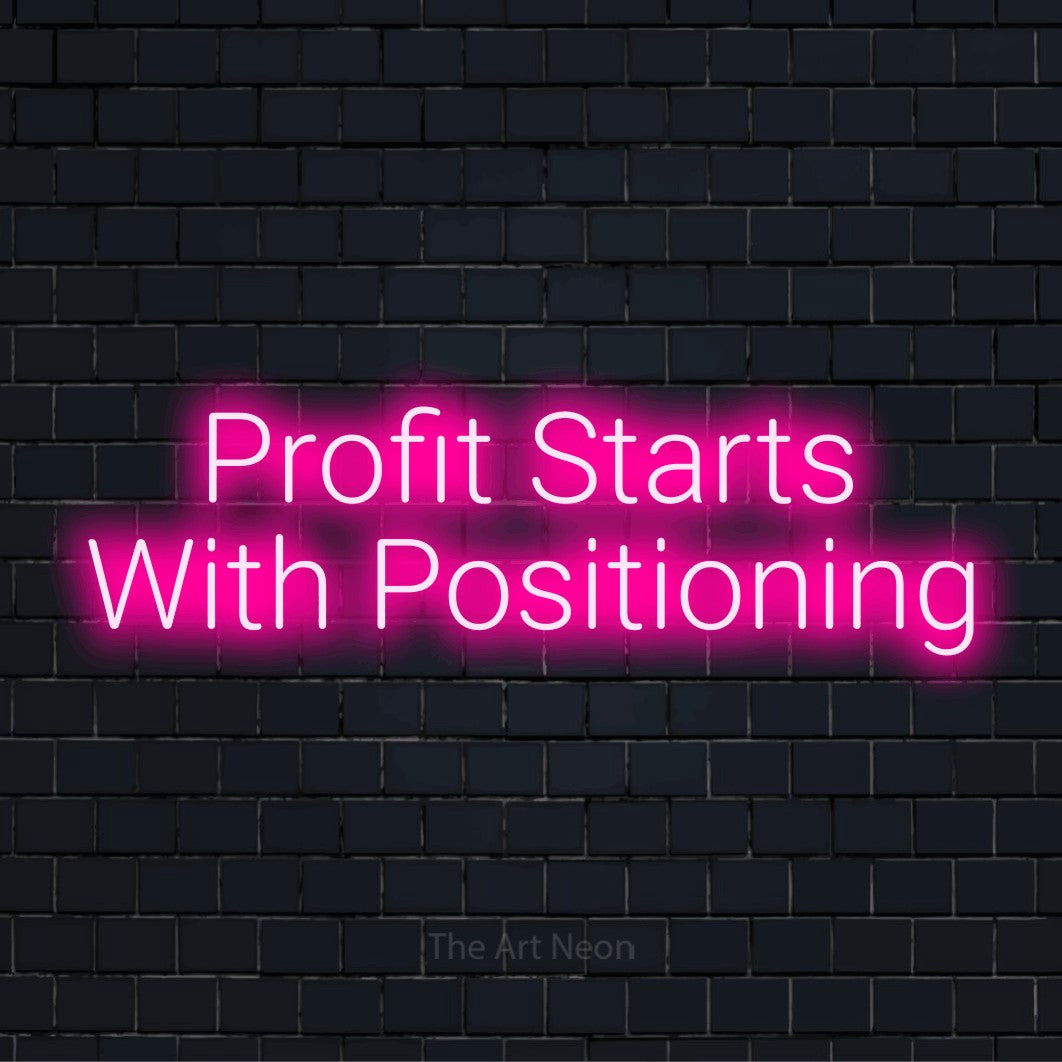 "Profit Starts With Positioning" LED neon sign on a black brick wall
