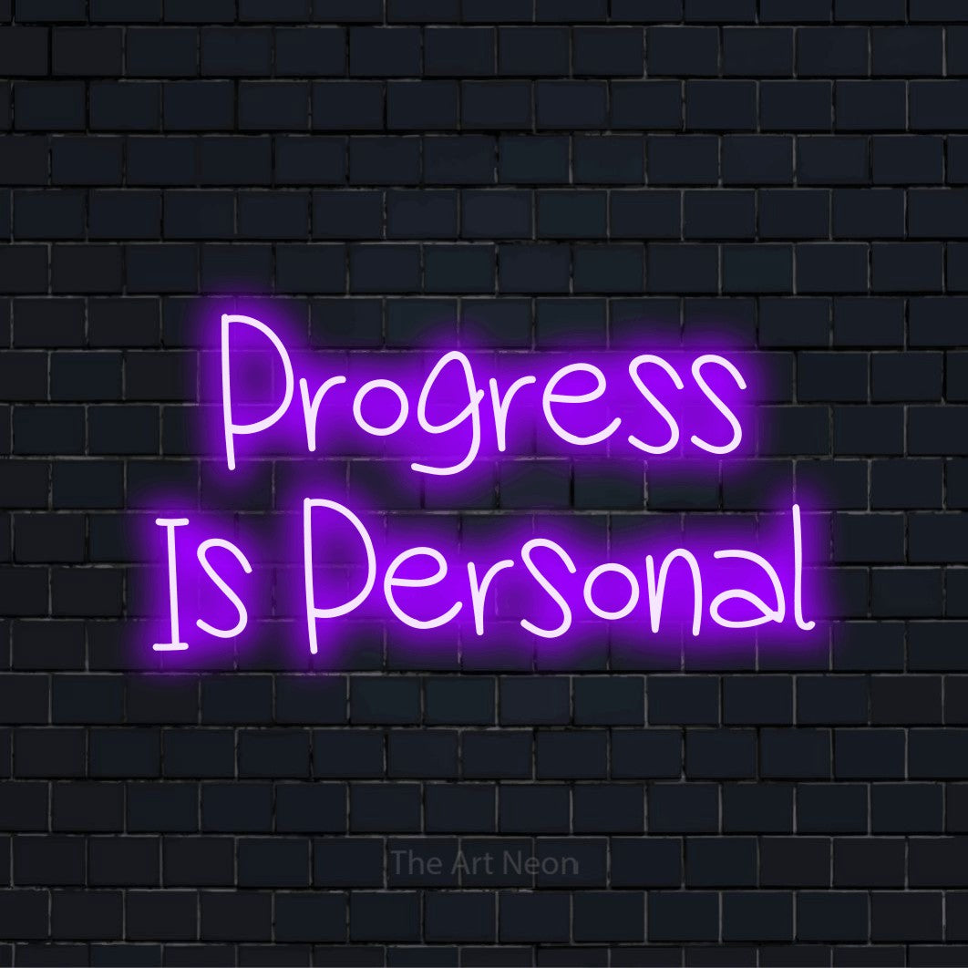 "Progress Is Personal" script-style LED neon sign on a black brick wall