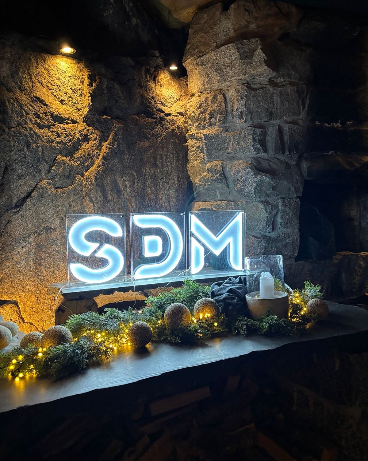 Custom SDM logo LED neon sign installed against a stone wall