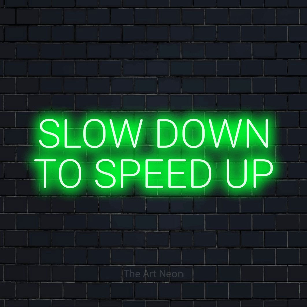 "Slow Down To Speed Up" text design with neon effect on a black brick wall